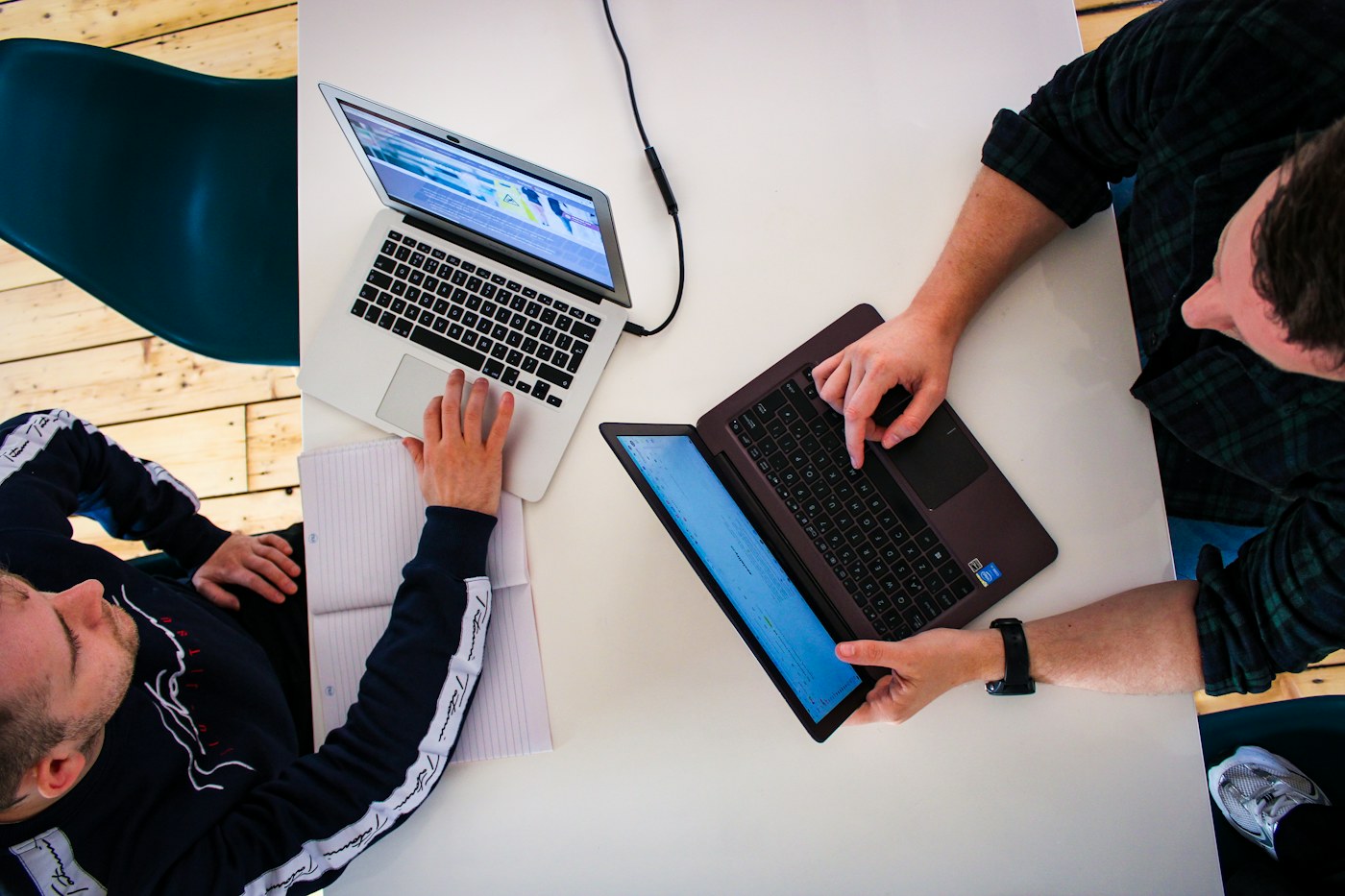 Zwei Fachkräfte arbeiten gemeinsam mit Laptop und Tablet an digitalen Aufgaben